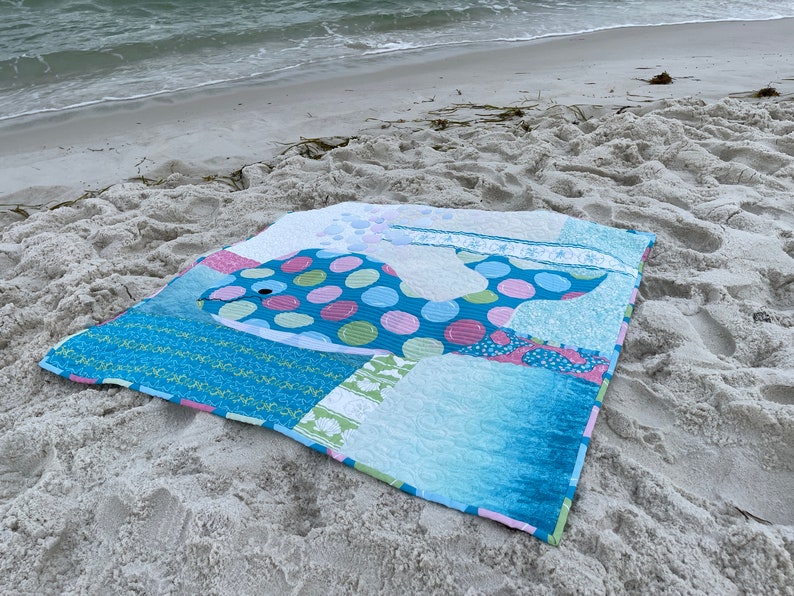 BUBBLES baby whale quilt on the beach with surf.