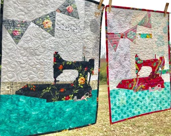 May include: Two rectangular fabric wall hangings featuring quilted patterns. One displays a black sewing machine with floral accents on a white and teal background, while the other shows a red sewing machine on a white and teal background.