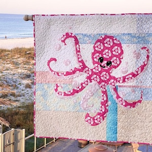Octopus applique quilt hanging at beach scene and made with one focus fabric on a background of eleven scrappy fabrics.