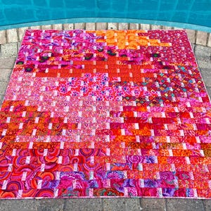 Peut inclure: Une courtepointe vibrante et faite à la main avec un motif tissé. La courtepointe présente un patchwork de différents tissus dans des tons de rose, de rouge et d'orange. La courtepointe est rectangulaire et semble être en coton. La courtepointe mesure environ 178 cm sur 203 cm.