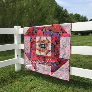 Dash About nestled churn dash quilt hanging on fence.