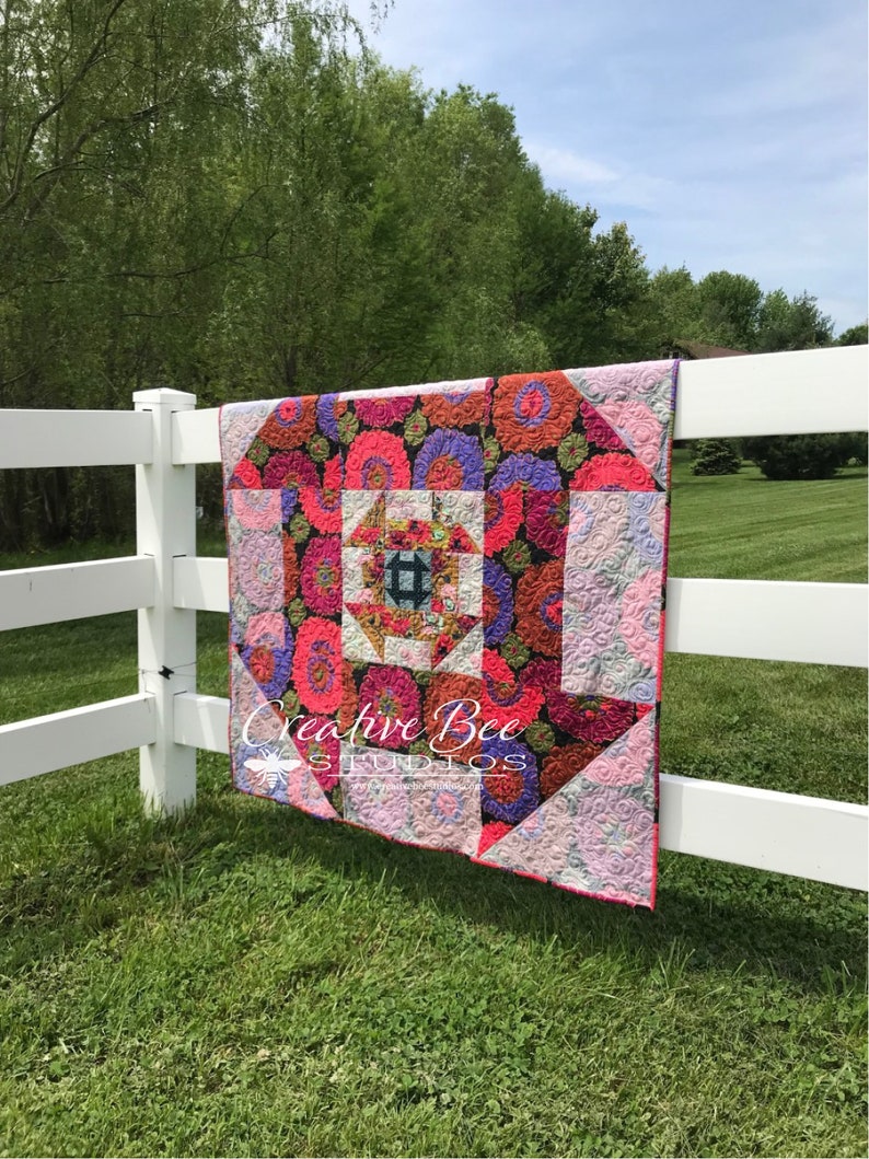 Dash About nestled churn dash quilt hanging on fence.