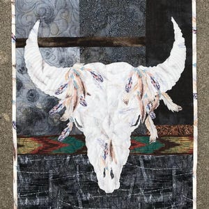 Full view of bison quilt with feather focus fabric and dark background fabrics.