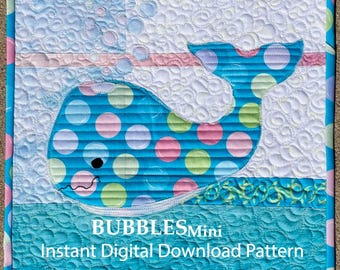 May include: A square quilted wall hanging featuring a blue whale with multicolored polka dots. The background has white and teal sections with swirling stitch patterns. Text reads BUBBLESMini Instant Digital Download Pattern.