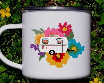 May include: A white enamel mug with a silver rim featuring a graphic of a white camper trailer with the name Rosie printed in red. The camper is surrounded by a colorful illustration of various flowers in shades of pink, yellow, and blue.
