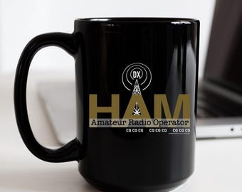 May include: Black ceramic coffee mug with a gold graphic of a radio antenna and the text "HAM Amateur Radio Operator" with the letters "CO" repeated several times.
