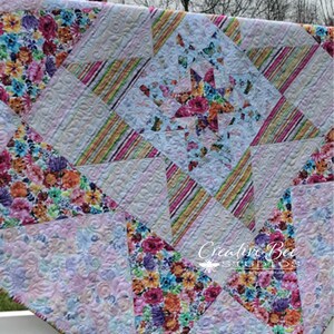 Quilt hanging on-point on fence.