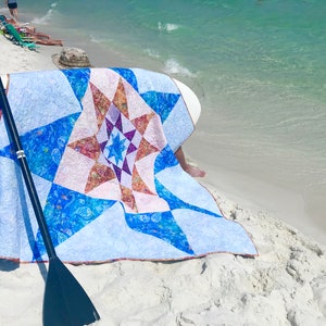 Variable star quilt shown on beach for pdf pattern download.