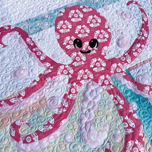 Detailed view of octopus applique quilt pattern made with both sides of pink fishbone and sand dollar fabric.