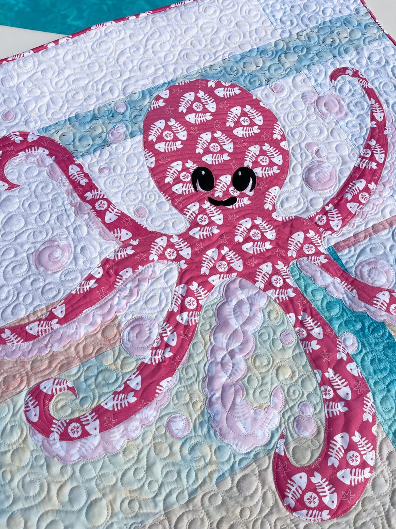 Detailed view of octopus applique quilt pattern made with both sides of pink fishbone and sand dollar fabric.
