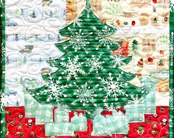 May include: A green quilted Christmas tree with white snowflakes and presents underneath. The tree is surrounded by a red and white quilted background with a variety of Christmas-themed patterns.