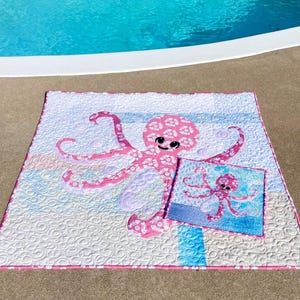 PINKY and Pinky Mini octopus applique quilt pattern made with both sides of pink fishbone and sand dollar fabric shown at poolside.