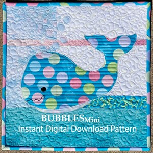 May include: A blue whale with pink and green polka dots swims in a blue ocean with white bubbles. The whale is surrounded by a white background with a pink and white stripe. The text "BUBBLES Mini Instant Digital Download Pattern" is at the bottom of the image.