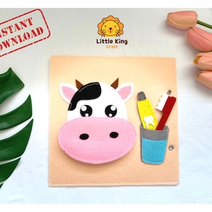 Puede incluir: Una actividad de manualidades de fieltro para niños con una vaca con la nariz rosa, un cepillo de dientes y un tubo de pasta de dientes. La manualidad está sobre un fondo de fieltro beige.