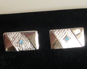 Gemelos vintage plateados con diamantes de imitación azules sobre fondo texturizado, cierre de palanca, de Sarah Coventry.