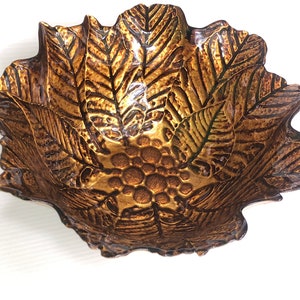 May include: A gold-colored bowl with a leaf design. The bowl is made of a natural material, possibly coconut.