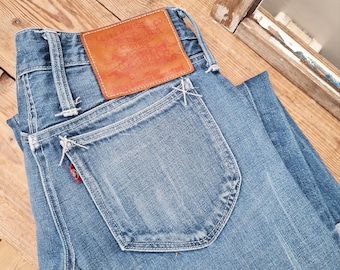 May include: A pair of blue denim jeans with a brown leather patch that reads "Levi Strauss & Co. Original  Riveted Clothing" and "San Francisco, Cal.  Pat. Apr. 20, 1873.  The Genuine Levi Strauss & Co.  Trade Mark Registered."