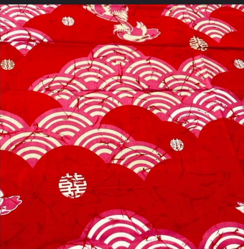May include: Red fabric with a white and pink pattern of overlapping circles and the Chinese character for "double happiness" repeated throughout.