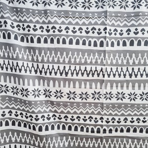 May include: Gray and white fabric with a repeating geometric pattern. The pattern includes snowflakes, zigzags, arches, and other abstract shapes.