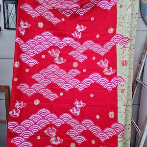 Puede incluir: Tela roja con un patrón repetido de olas rosas y blancas, peces estilizados y el carácter chino para "doble felicidad".