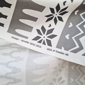 May include: White fabric with a black and gray geometric pattern. The fabric has a design by Jennifer Idrizi 2016 and the text "IKEA of Sweden AB".