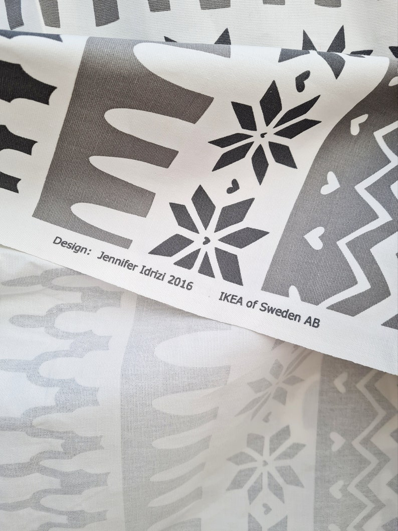 May include: White fabric with a black and gray geometric pattern. The fabric has a design by Jennifer Idrizi 2016 and the text "IKEA of Sweden AB".