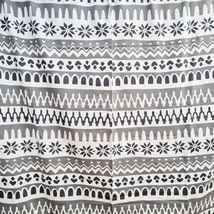 May include: Gray and white fabric with a repeating geometric pattern. The pattern includes snowflakes, arches, and zigzags.