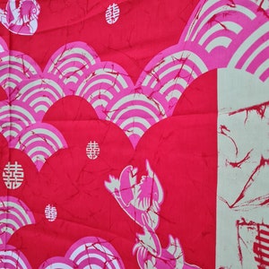 May include: Red fabric with a white and pink pattern of stylized waves and Chinese characters. The fabric also features a stylized image of a fish.