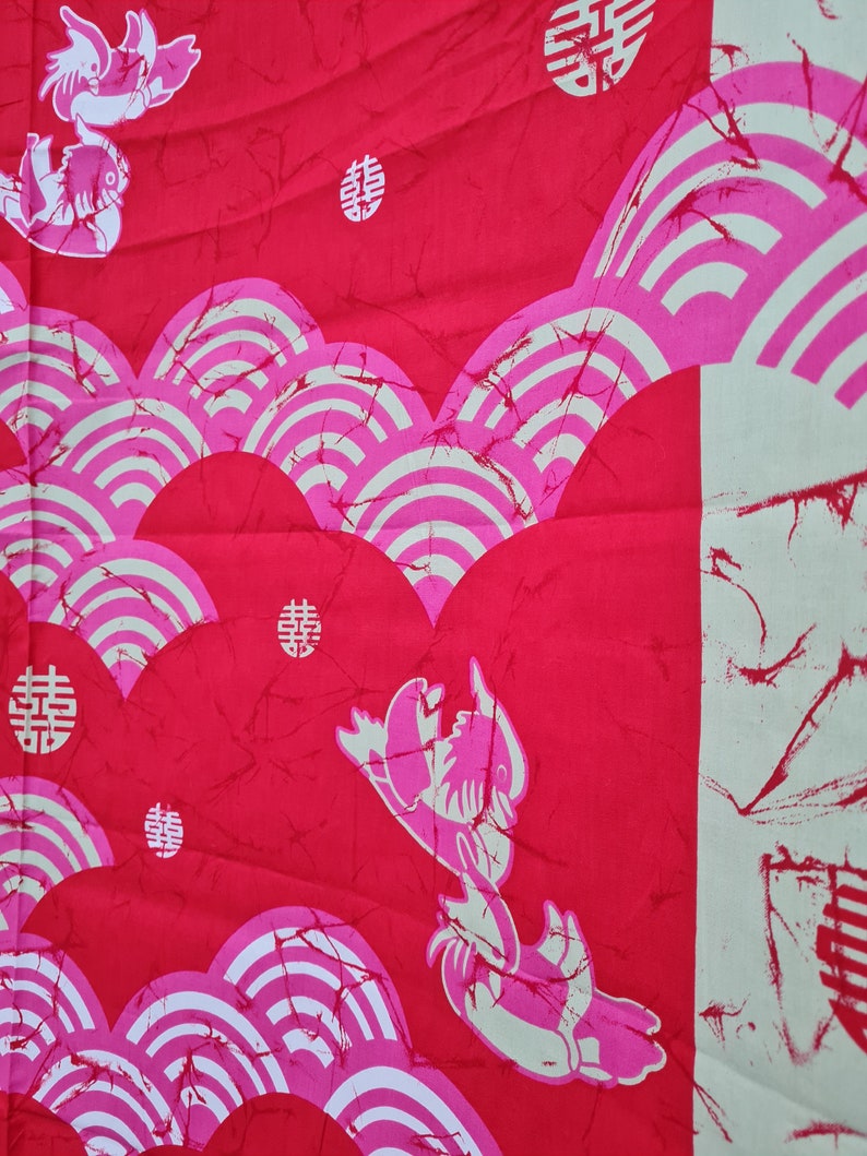 May include: Red fabric with a white and pink pattern of stylized waves and Chinese characters. The fabric also features a stylized image of a fish.