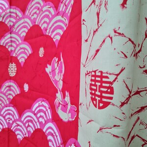 May include: Red fabric with a white and pink pattern of stylized waves and a Chinese character for "double happiness".
