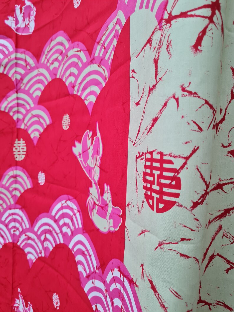 May include: Red fabric with a white and pink pattern of stylized waves and a Chinese character for "double happiness".