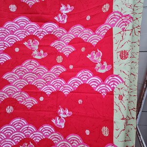 May include: Red fabric with a repeating pattern of pink and white waves, stylized fish, and a Chinese character that means "double happiness".