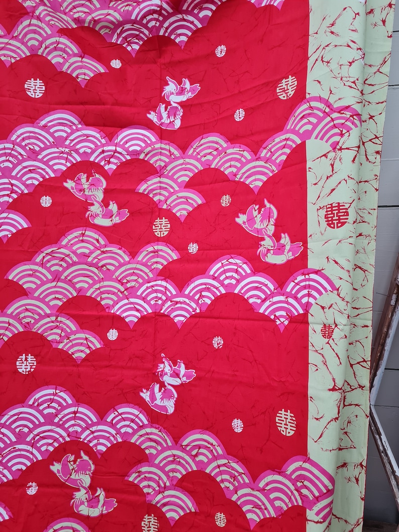 May include: Red fabric with a repeating pattern of pink and white waves, stylized fish, and a Chinese character that means "double happiness".