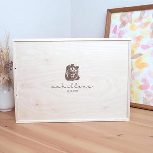 Peut inclure: Une boîte en bois avec un motif de tête de lion et le texte "achilleas 11.12.2020".