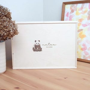 Peut inclure: Une boîte en bois blanche avec une illustration de panda et le nom "Mateo" avec la date "08.10.2024" inscrite sur le devant.