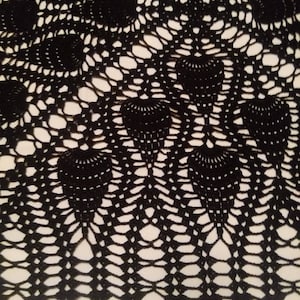 May include: Black crocheted doily with a circular design featuring a repeating pattern of small circles and larger, fan-shaped motifs.