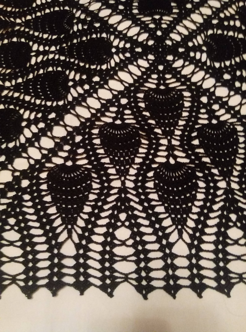 May include: Black crocheted doily with a circular design featuring a repeating pattern of small circles and larger, fan-shaped motifs.