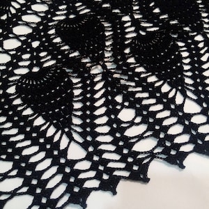 May include: Black crochet doily with a delicate, intricate pattern. The doily has a scalloped edge and is made with fine yarn.
