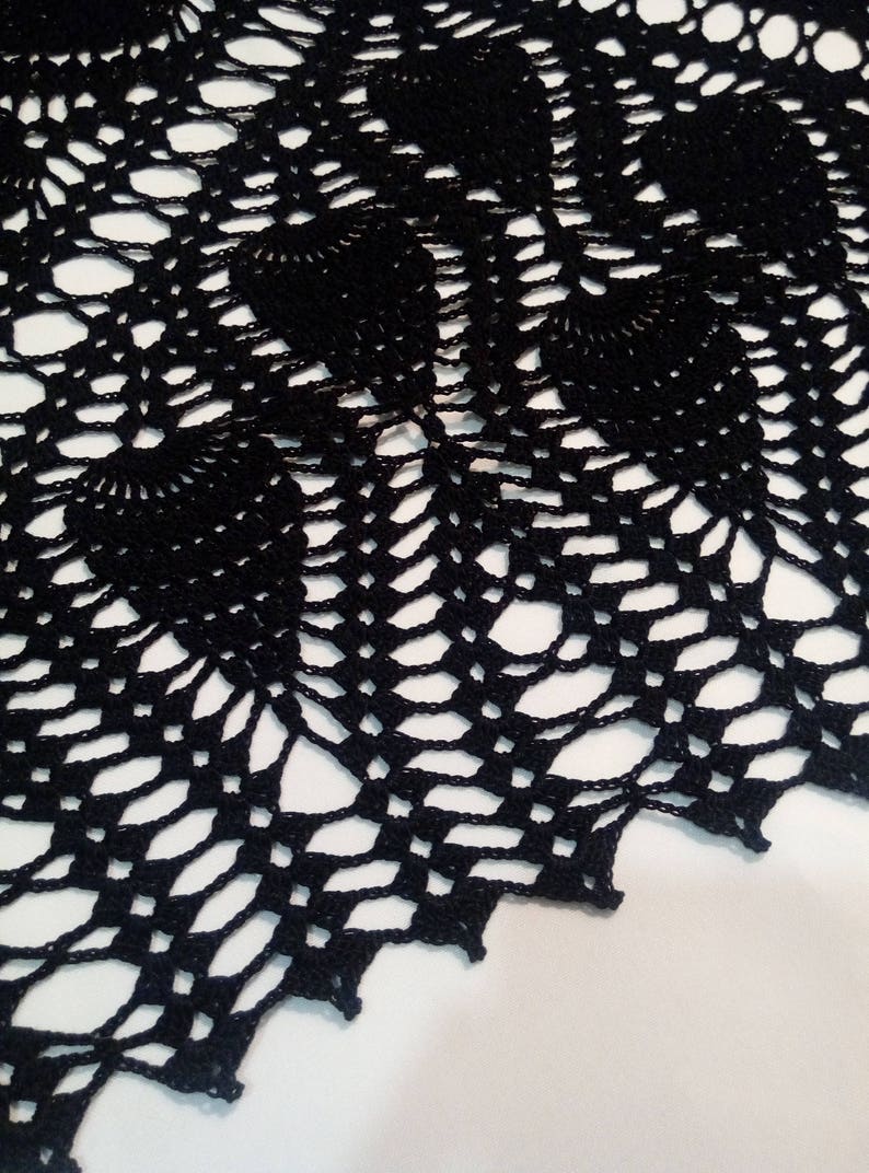 May include: Black crochet doily with a delicate, intricate pattern. The doily has a scalloped edge and is made with fine yarn.