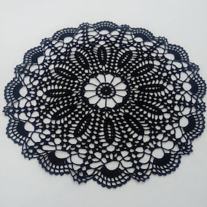 May include: A black crocheted doily with a delicate floral design. The doily is circular and has a lace-like pattern.