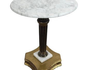 May include: A round white marble top table with a gold base. The base is a fluted column with a star-shaped base.