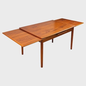 May include: A rectangular wooden dining table with a warm brown finish and visible wood grain patterns. The table features two extendable side leaves that pull out from beneath the main surface, supported by four tapered cylindrical legs.
