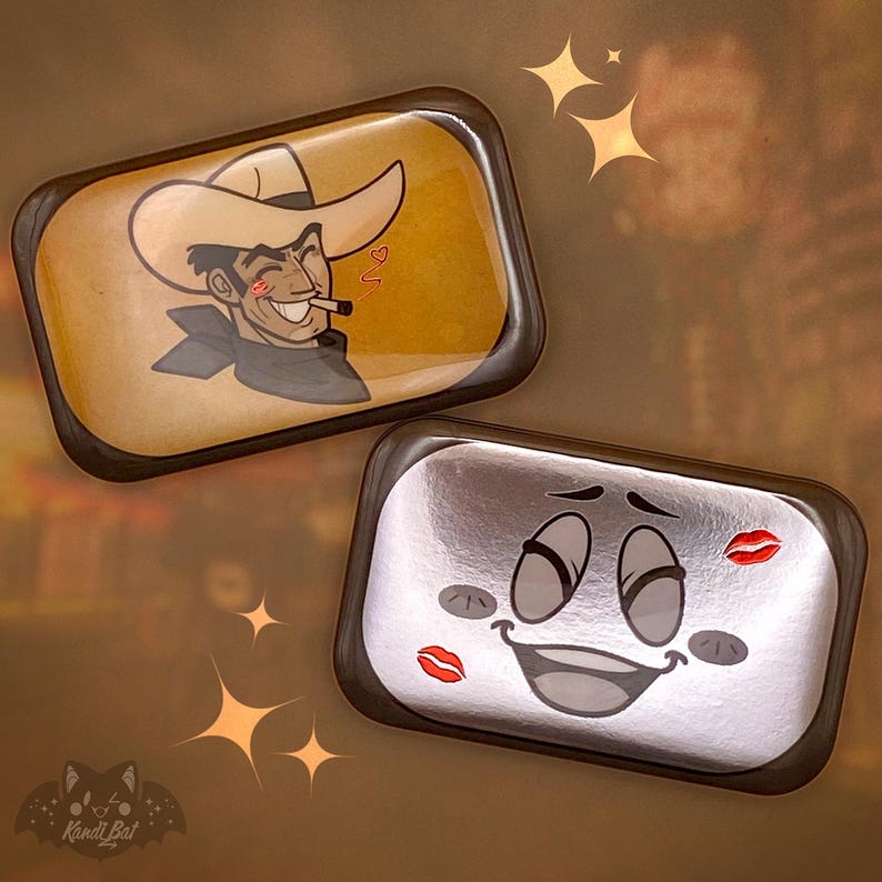 May include: Two rectangular trays with cartoon designs. One features a cowboy with a hat, a cigarette, and a heart. The other has a smiling face with red lipstick kisses. Both trays have a brown border and a metallic background.