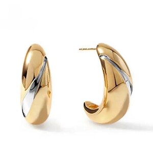 May include: A pair of gold hoop earrings with a white stripe design. The earrings are made of two-toned metal.