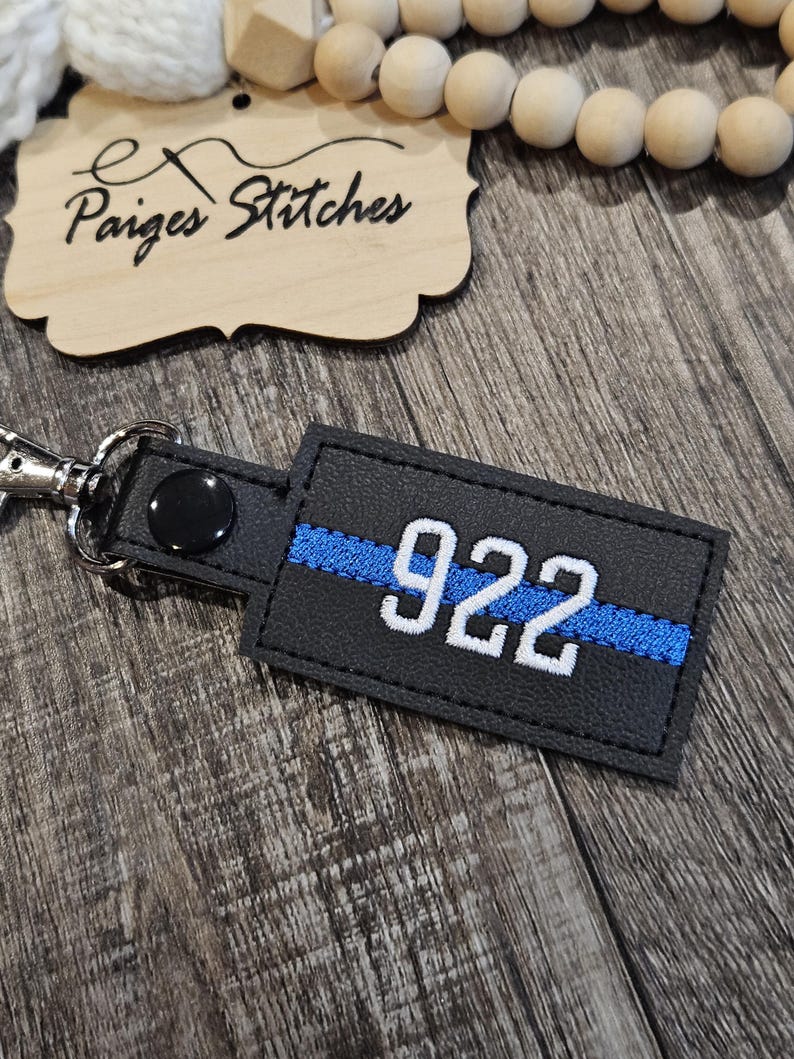 May include: Black leather keychain with a blue thin blue line and the number 922 in white.