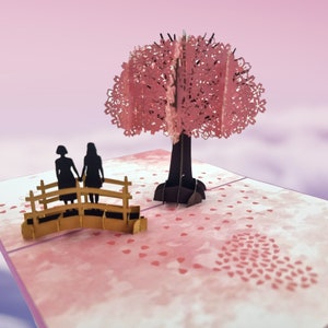 Biglietto pop-up 3D con scena d'amore con fiori di ciliegio e donna dello stesso sesso