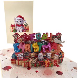 Peut inclure: Carte de No&euml;l pop-up avec un design festif. Elle pr&eacute;sente des chatons portant des chapeaux de P&egrave;re No&euml;l et entour&eacute;s de cadeaux. La carte &eacute;pelle "MERRY CHRISTMAS" en lettres color&eacute;es. Un chaton assorti est sur le devant.