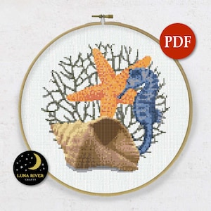 May include: Cross stitch pattern featuring a seashell, a blue seahorse, and an orange starfish. The design is surrounded by a brown coral branch.