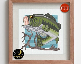 May include: A cross-stitch pattern featuring a green and white largemouth bass fish jumping over a brown branch against a light blue background. The design is framed in wood and includes a red PDF label and a black Luna River Crafts logo.