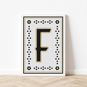 May include: Black and white tile print with a gold border featuring the letter "F" in a black and white tile pattern.